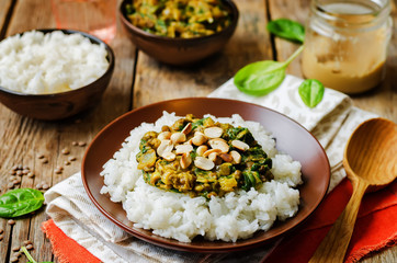 lentils, peanut butter spinach curry with rice on a wood background