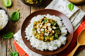 lentils, peanut butter spinach curry with rice on a wood background