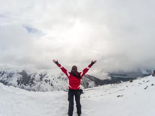  Woman raising arms on top of the snowy mountain