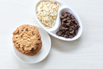 Oatmeal cookies and chocolate chips on light background