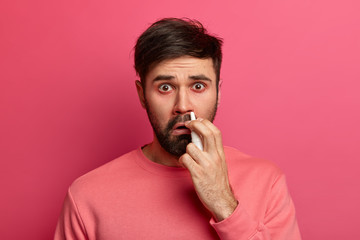 People, cold symptoms and medication concept. Unhappy sick man uses nose drops, has rhinitis and...