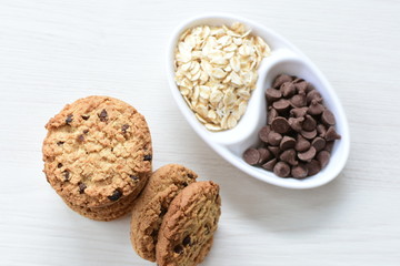 Oatmeal cookies and chocolate chips on light background