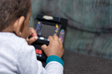 Fototapeta na wymiar Child Playing Small Video Game Unit