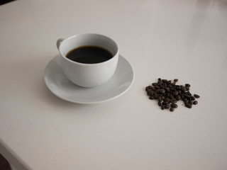 Cup of coffee with coffee beans on table