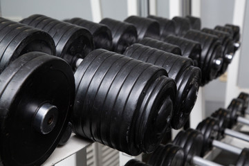 Black dumbbells for fitness classes in the gym.