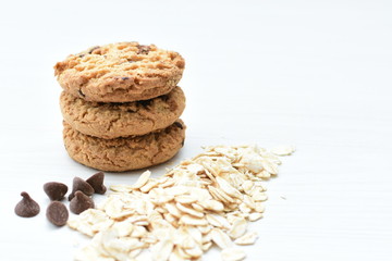 Oatmeal cookies and chocolate chips on light background
