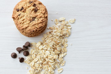 Oatmeal cookies and chocolate chips on light background