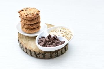 Oatmeal cookies and chocolate chips on light background