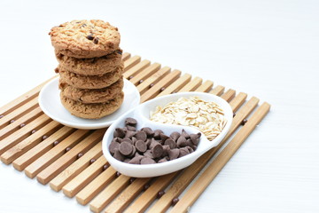 Oatmeal cookies and chocolate chips on light background
