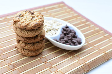 Oatmeal cookies and chocolate chips on light background