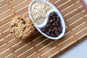 Oatmeal cookies and chocolate chips on light background