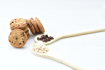 Oatmeal cookies and chocolate chips on light background