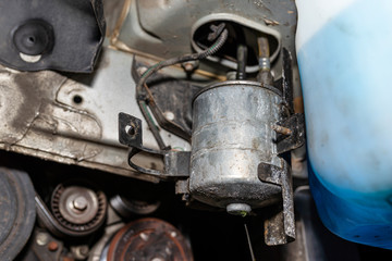 Fototapeta premium Worn fuel filter installed in the car in the wheel arch, visible dripping fuel from the bottom of the filter.