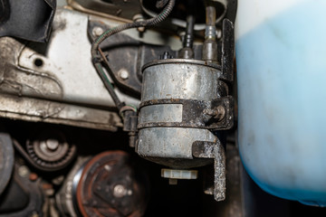 Worn fuel filter mounted and screwed on the car in the wheel arch.