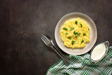 Mashed potatoes in a bowl with greens and milk on a dark background. View from above, flat lay, place for your text.