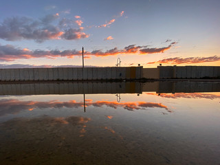 Beautiful moment. A reflection of colorful clouds and concrete wall over calm water.