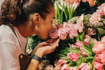 Close up of a woman smelling the flowers in the flower shop.