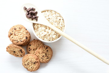 Oatmeal cookies and chocolate chips on light background