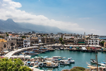 Fototapeta na wymiar beautiful view of kyrenia harbour, ship, buildings, mountains and blue sky with clouds on the background