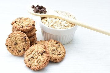 Oatmeal cookies and chocolate chips on light background