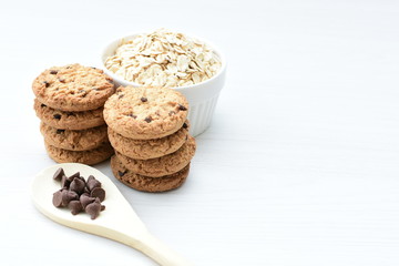 Oatmeal cookies and chocolate chips on light background