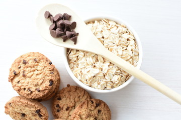 Oatmeal cookies and chocolate chips on light background