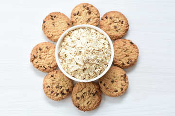 Oatmeal cookies and chocolate chips on light background