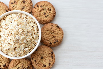 Oatmeal cookies and chocolate chips on light background