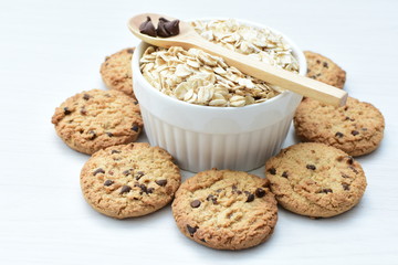 Oatmeal cookies and chocolate chips on light background