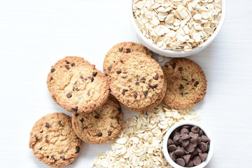 Oatmeal cookies and chocolate chips on light background