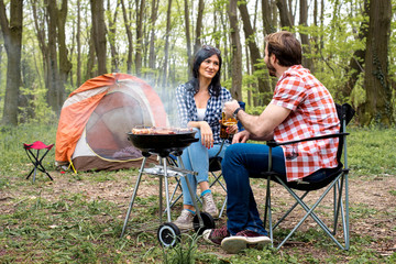 Couple camping, making barbecue and spending time together in nature