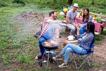 Group of friends making barbecue and having fun in nature