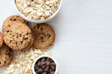 Oatmeal cookies and chocolate chips on light background