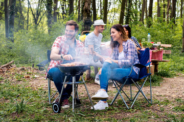 Friends hanging out having fun while making barbecue in nature
