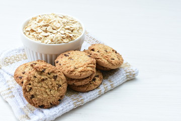 Oatmeal cookies and chocolate chips on light background