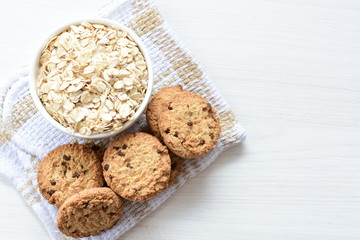 Oatmeal cookies and chocolate chips on light background