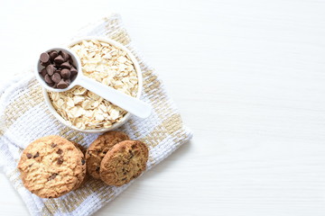 Oatmeal cookies and chocolate chips on light background