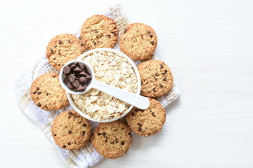 Oatmeal cookies and chocolate chips on light background