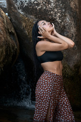 Joven morena de pelo de pie posando junto a las rocas en las montañas mojada dentro del agua...