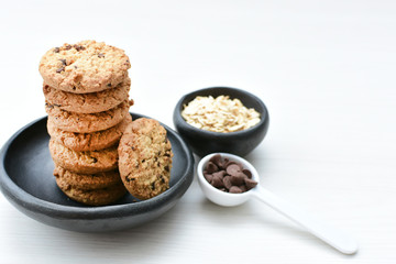 Oatmeal cookies and chocolate chips on light background