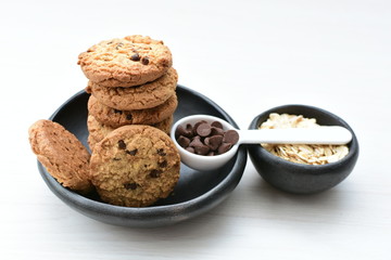 Oatmeal cookies and chocolate chips on light background