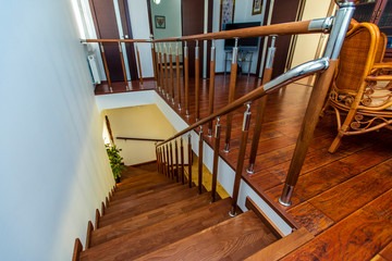 A beautiful wooden staircase of dark wood leading from the second floor to the first. Chrome shiny railing