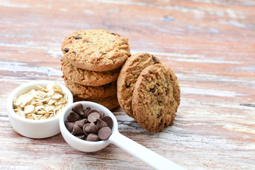 Oatmeal cookies and chocolate chips on light background