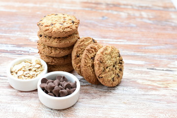 Oatmeal cookies and chocolate chips on light background