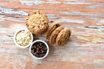 Oatmeal cookies and chocolate chips on light background