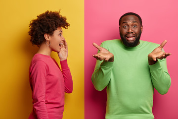 Disappointed black man spreads palms, looks hesitant and unhappy, faces problematic situation,...