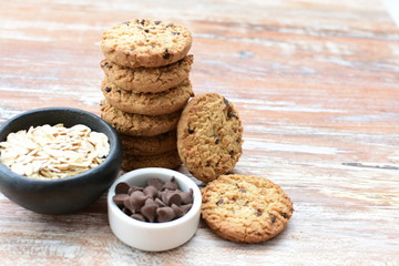 Oatmeal cookies and chocolate chips on light background