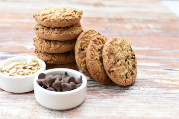 Oatmeal cookies and chocolate chips on light background