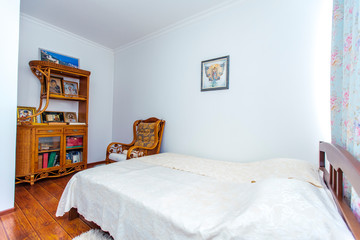 Prayer bedroom with a large double wooden bed, rocking chair and many Christian icons in the sideboard opposite the bed