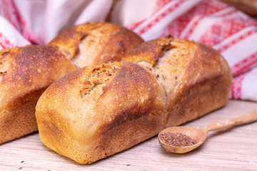 Traditional russian belorussian fresh fragrant bread on the table. Food concept. wooden spoon with flax seeds.